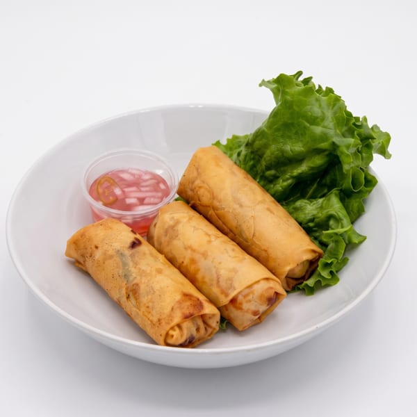 Three golden-brown spring rolls with lettuce and a side of pink dipping sauce on a white plate.